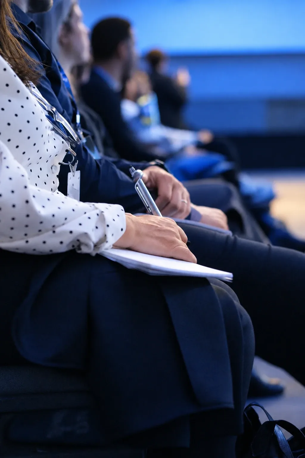 Detalhe de mãos fazendo anotações durante uma palestra